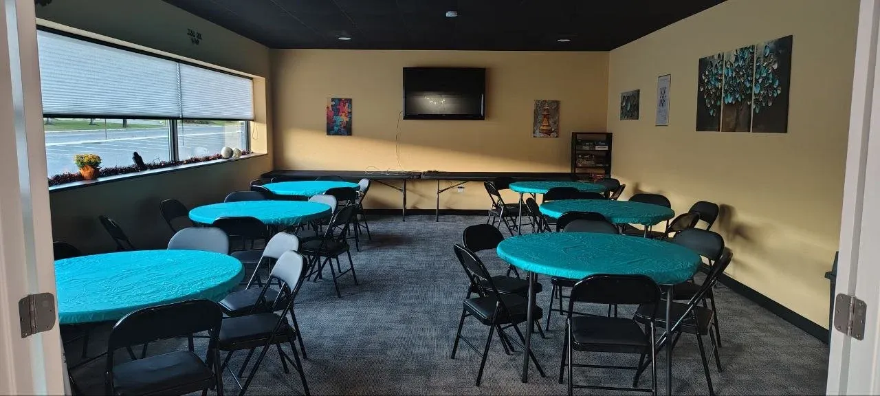 The Lock & Logic event space set up with round tables in teal tablecloths and folding chairs
